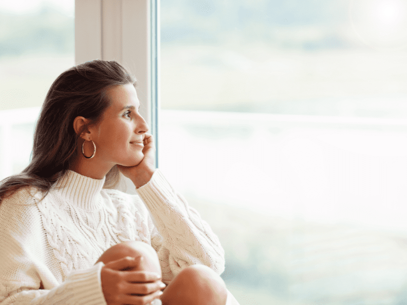 woman staring out large picture window